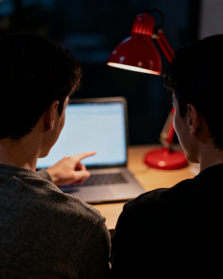 Zwei Menschen am Laptop, einer erklärt dem anderen etwas